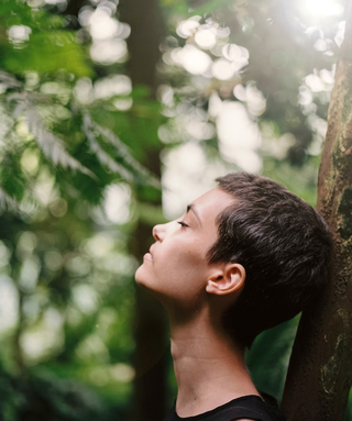 person leaning on tree (up close head shot)