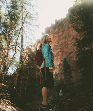 person in the forest looking up at the trees