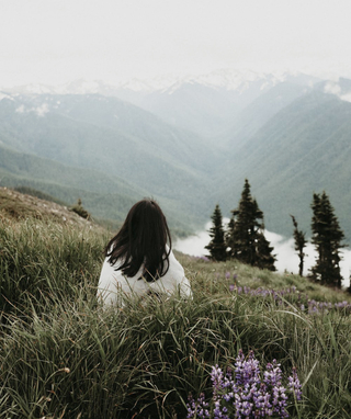 child sitting in a field overlooking the mountains